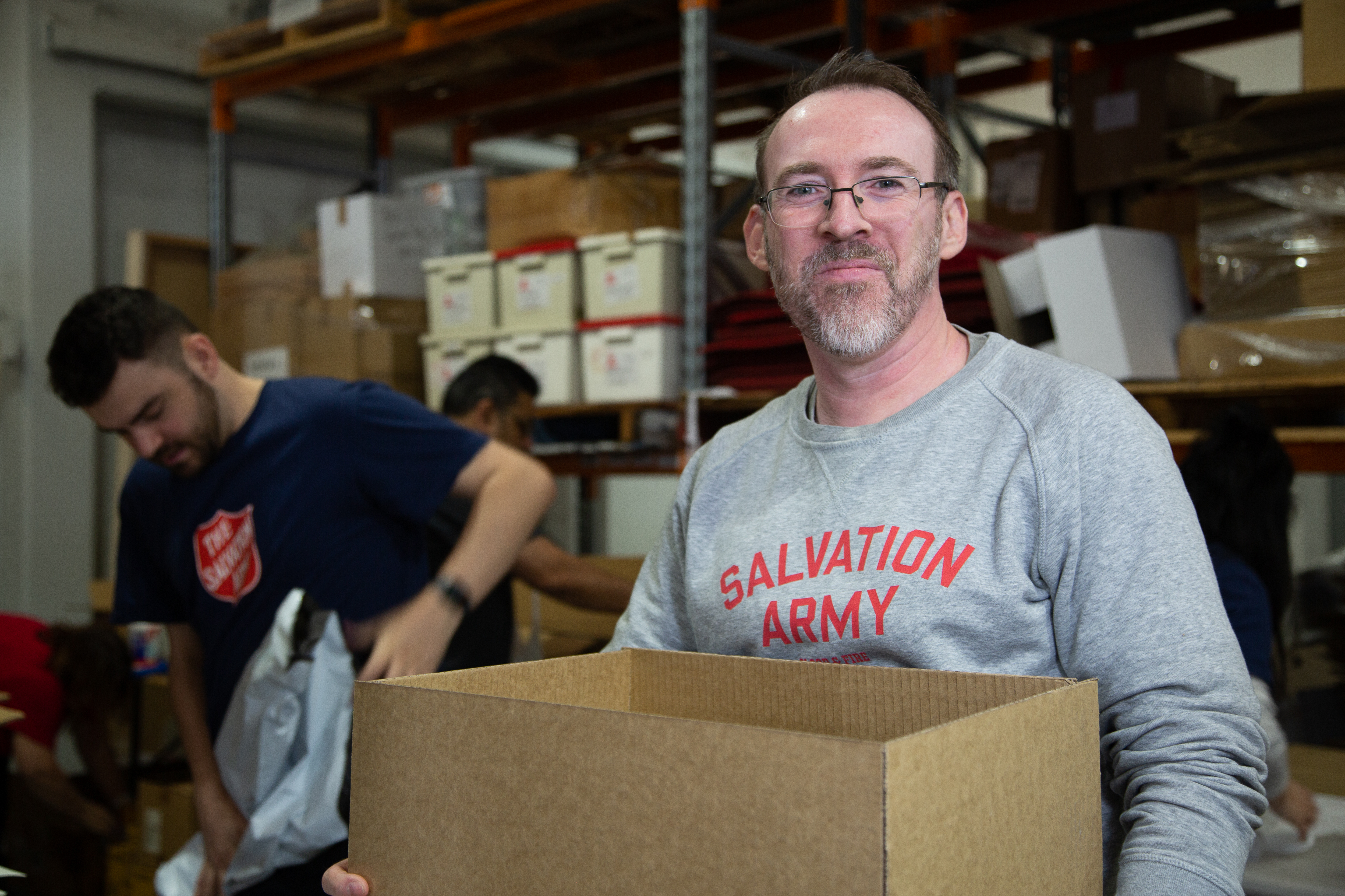 A Salvation Army volunteer carrying a box of supplies to serve the community.