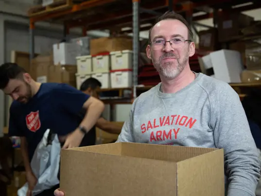 A Salvation Army volunteer carrying a box of supplies to serve the community.