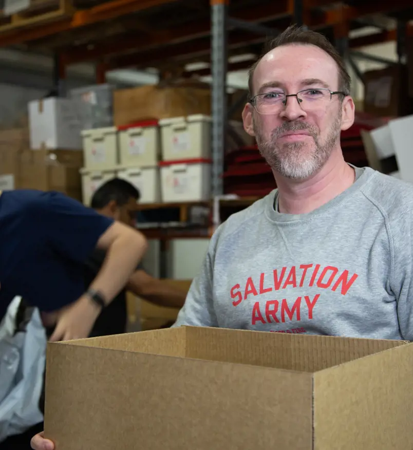 A Salvation Army volunteer carrying a box of supplies to serve the community.