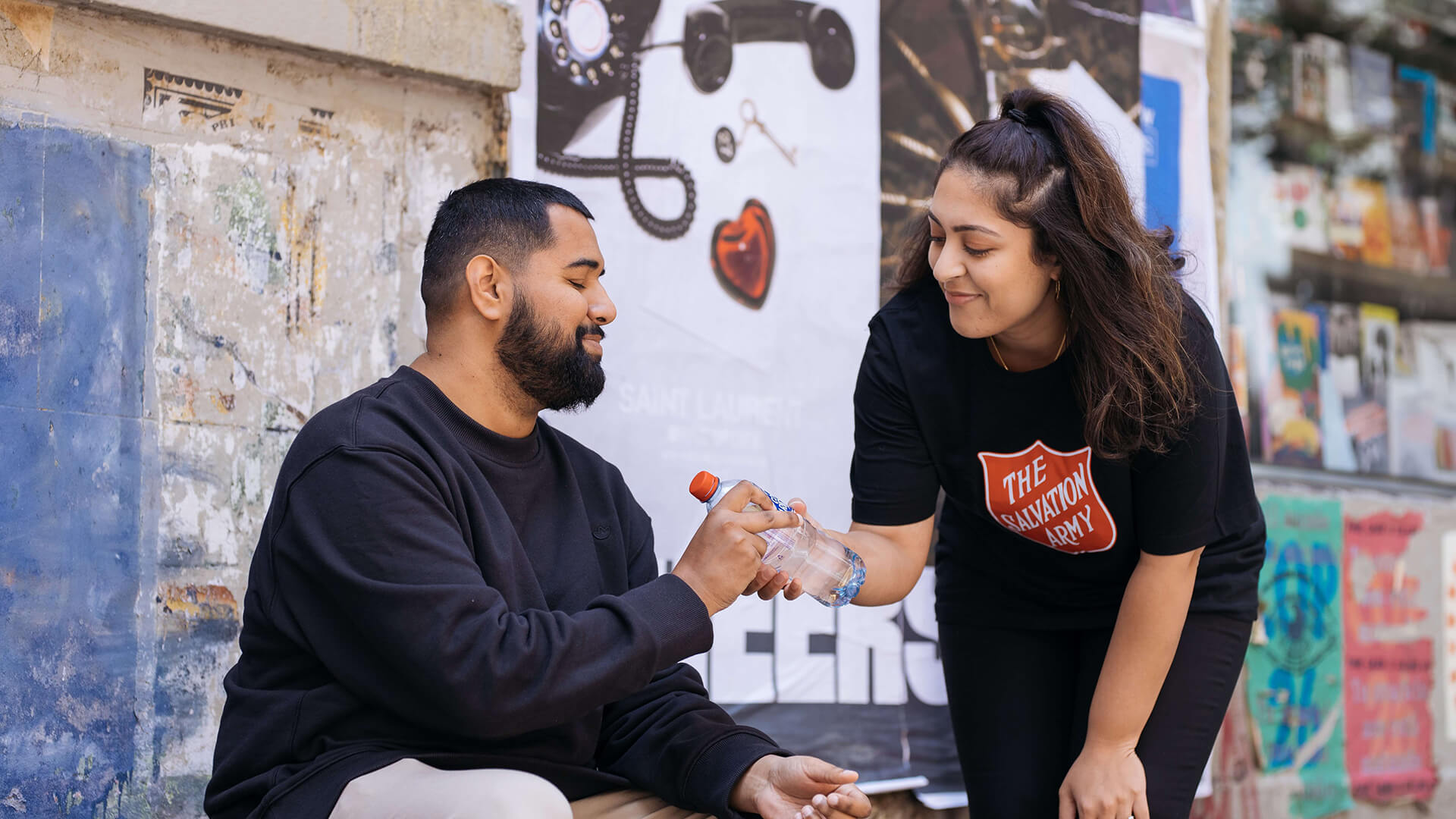 Salvation Army volunteer providing a man with bottled water.
