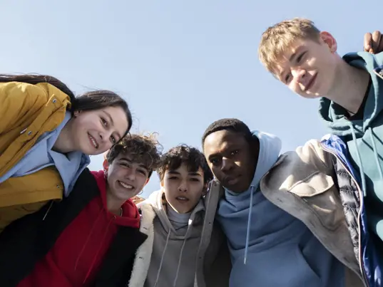 A group of young adults laughing and spending time together outdoors.