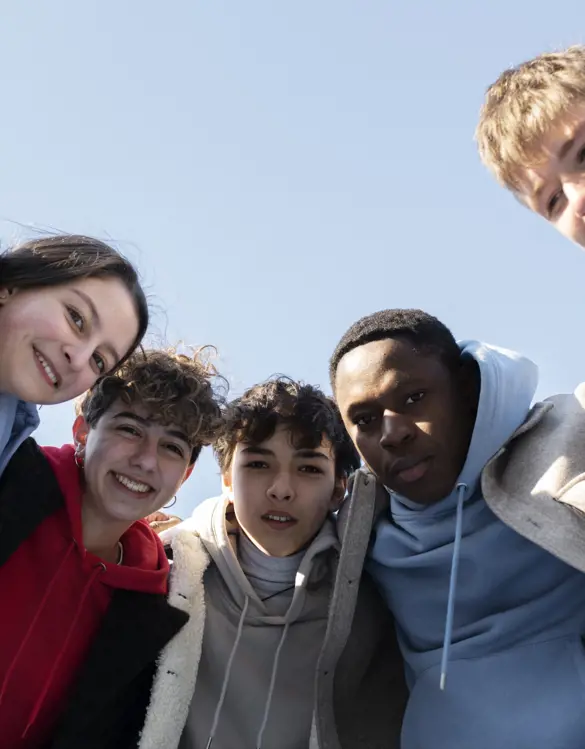 A group of young adults laughing and spending time together outdoors.