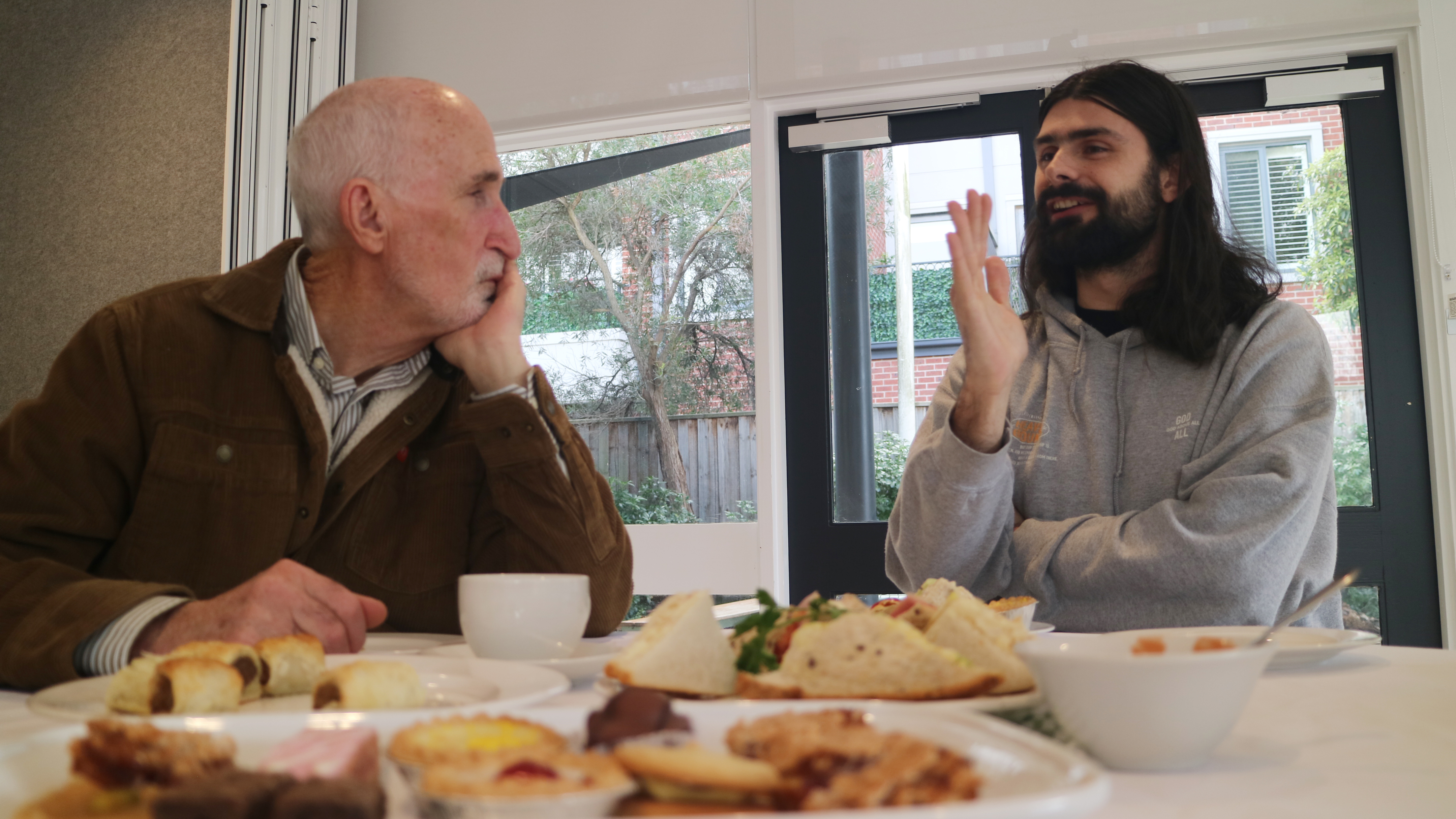 Two men sitting chatting together over morning tea