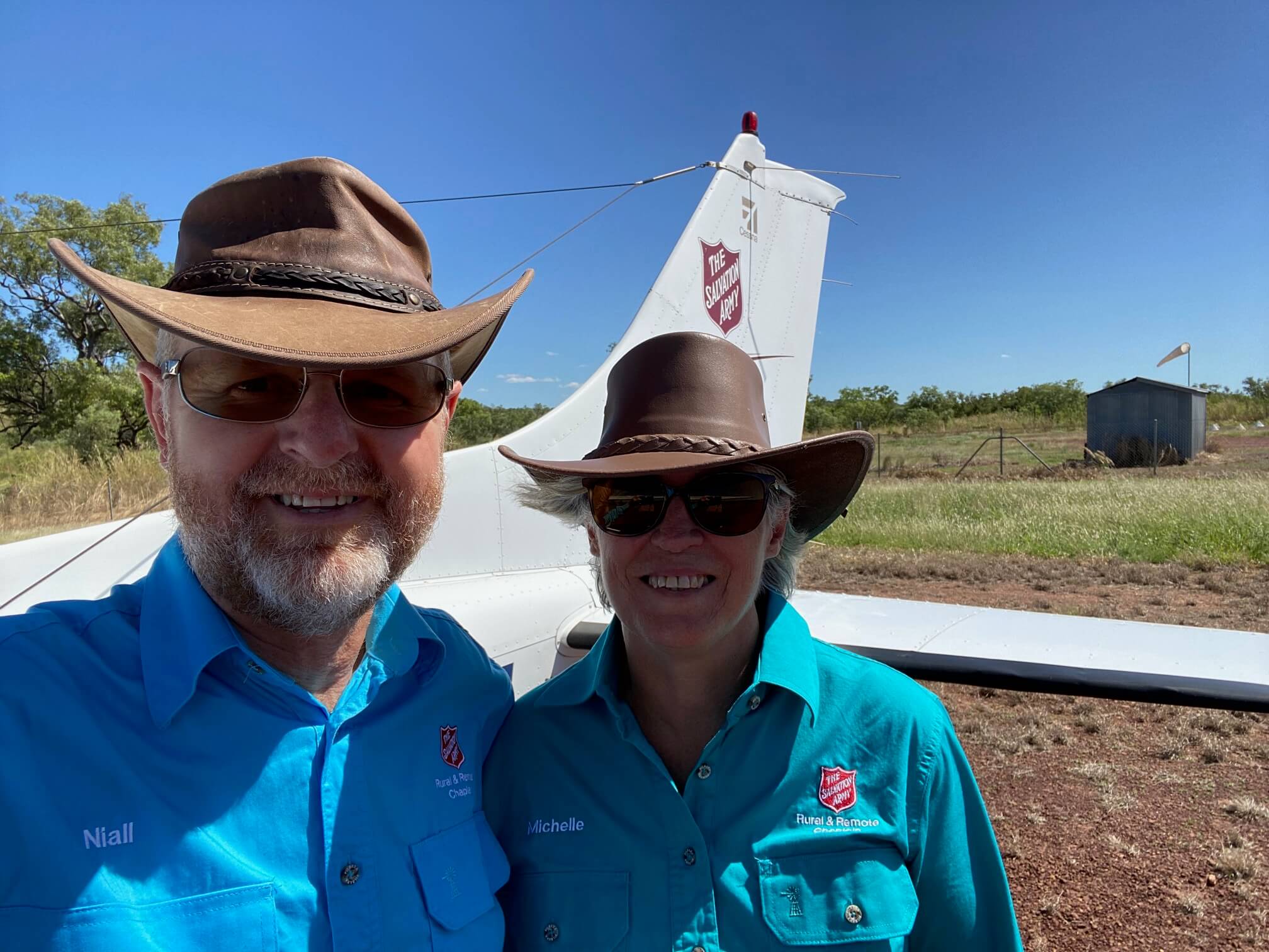 Flying Padre Majors Niall and Michelle Gibson standing in front of a Salvation Army branded plane for the Flying Padre. 