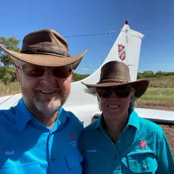 Flying Padre Majors Niall and Michelle Gibson standing in front of a Salvation Army branded plane for the Flying Padre.