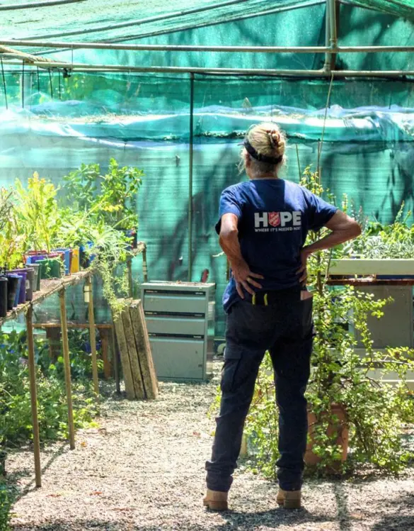 Garden of Hope banner image showing a Salvos worker standing in a greenhouse.