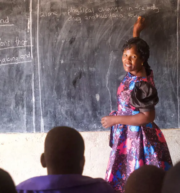 A colorfully dressed teacher directs her students