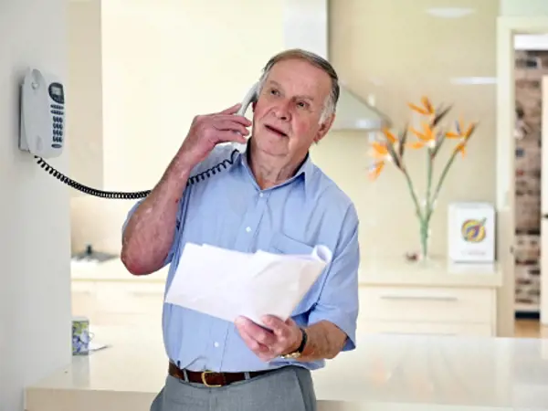 Man speaking on the phone while reviewing funeral paperwork at home