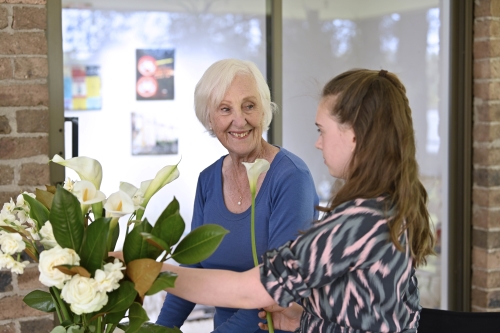 Grandmother and granddaughter arranging white flowers together