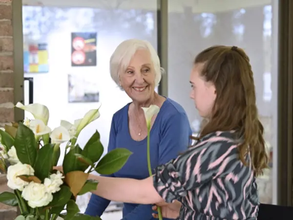 Grandmother and granddaughter arranging white flowers together