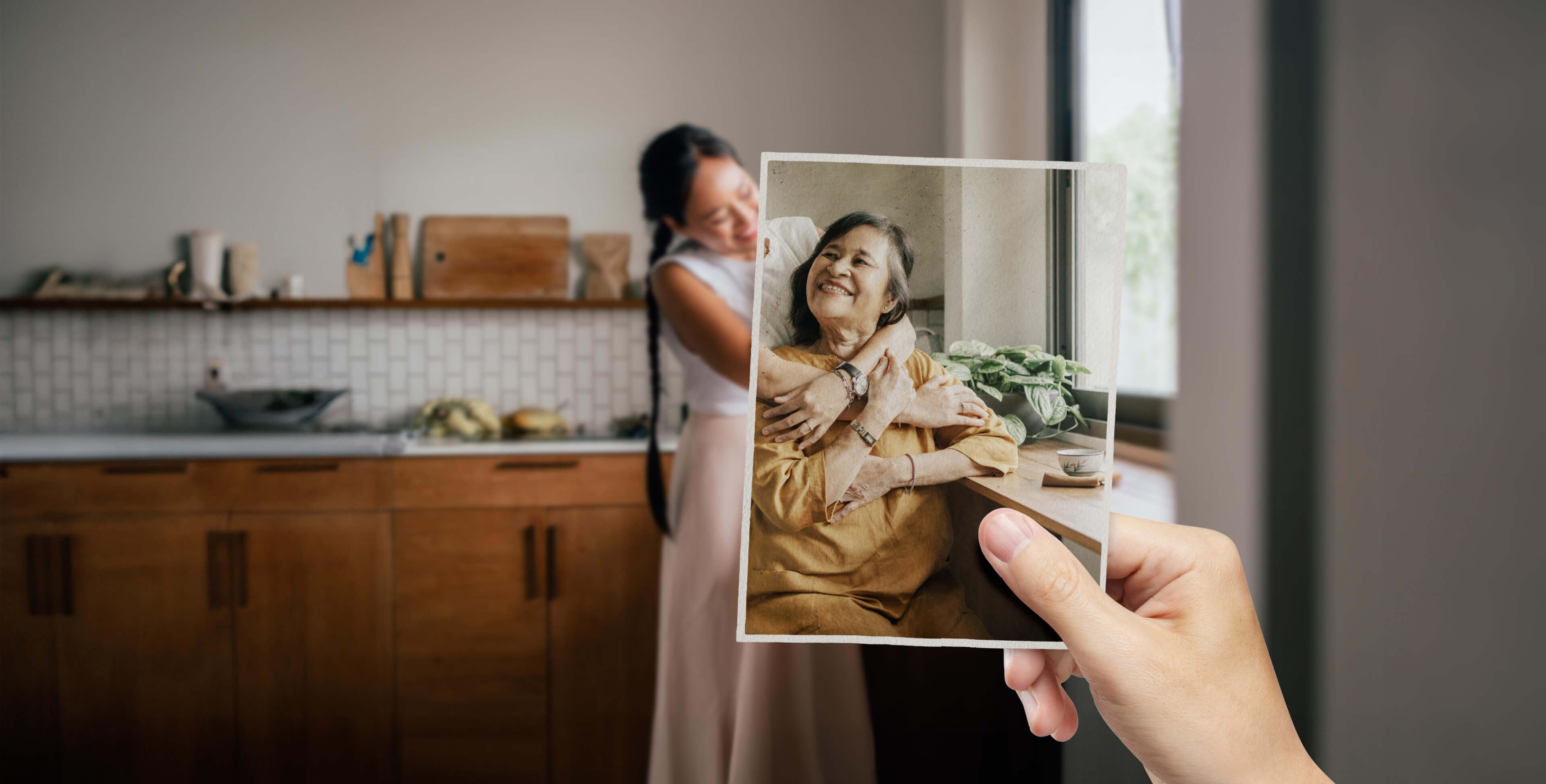 Daughter holding a photograph of her mother while embracing her at home