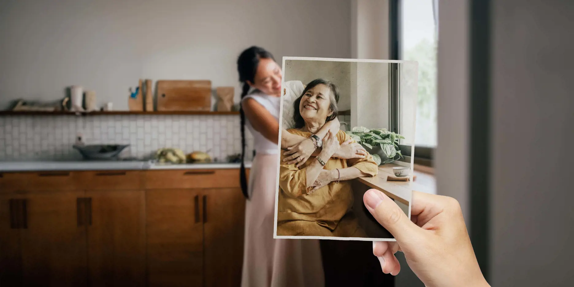 Daughter holding a photograph of her mother while embracing her at home