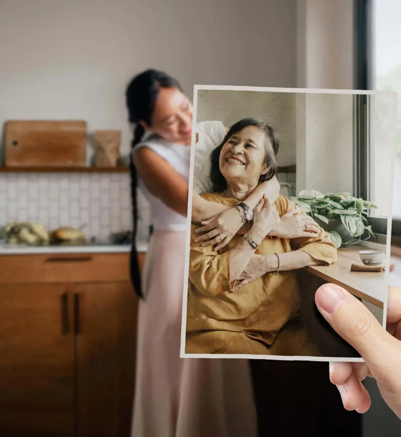 Daughter holding a photograph of her mother while embracing her at home