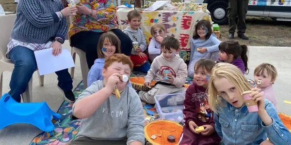 The travelling tea party - kids smiling while sitting on a mat outdoors
