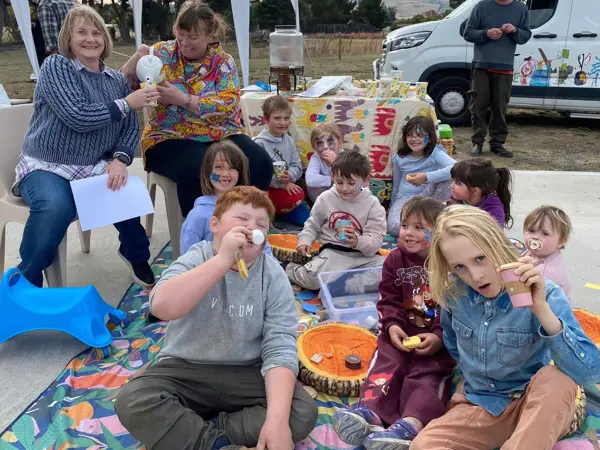 The travelling tea party - kids smiling while sitting on a mat outdoors