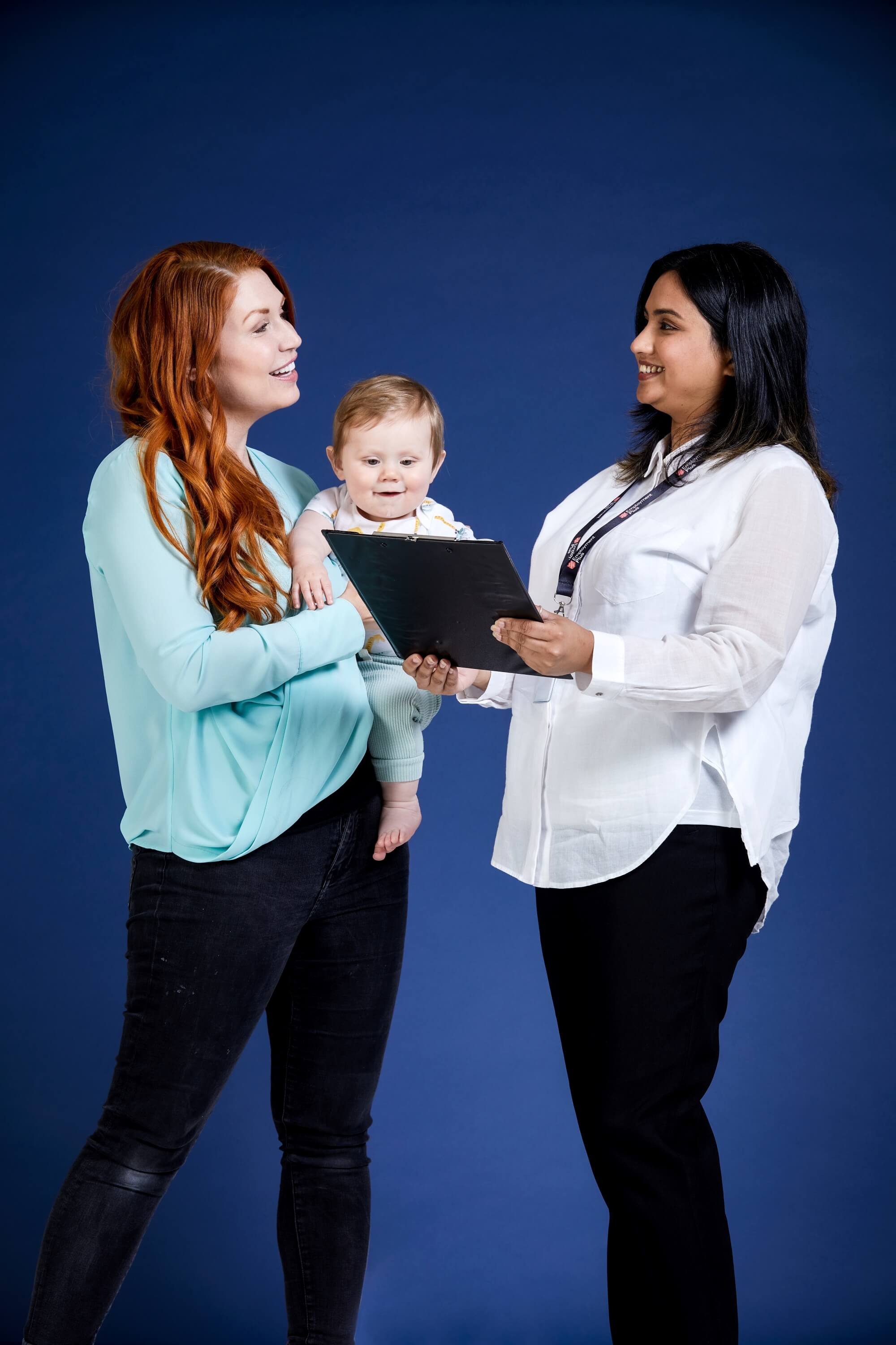 Mother with her baby talking to a parent pathways staff member who is holding a clipboard.