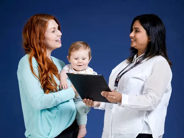 Mother with her baby talking to a parent pathways staff member who is holding a clipboard.