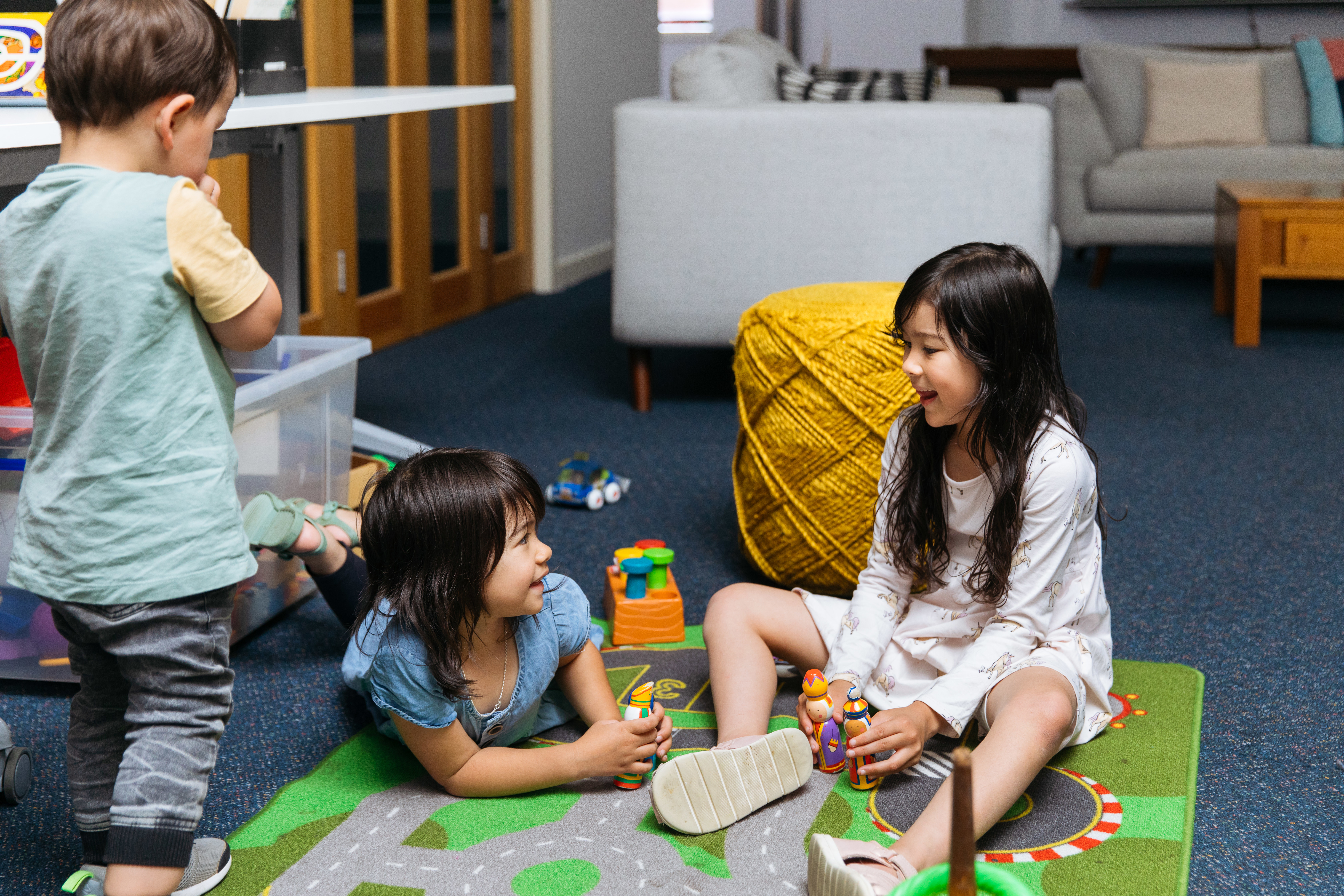 Three children similing as they play on a playmat. 