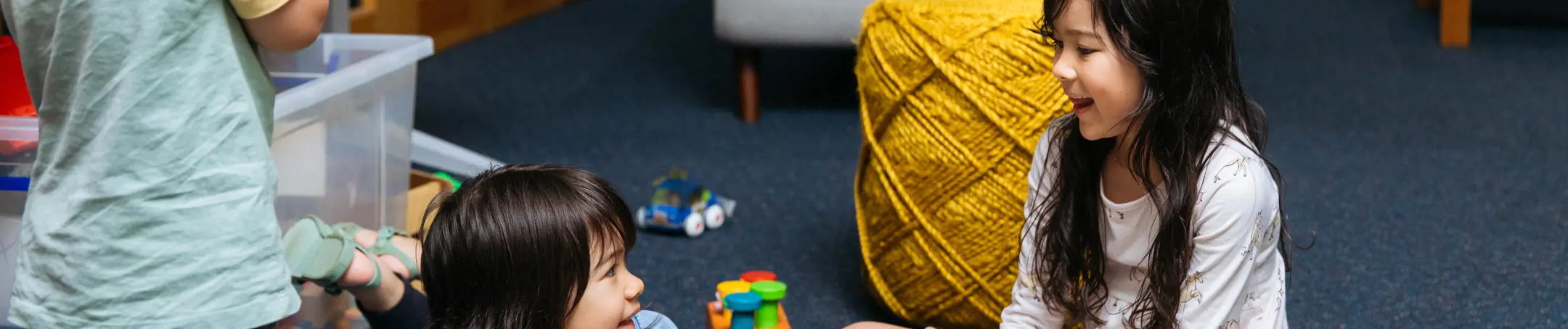 Three children similing as they play on a playmat.